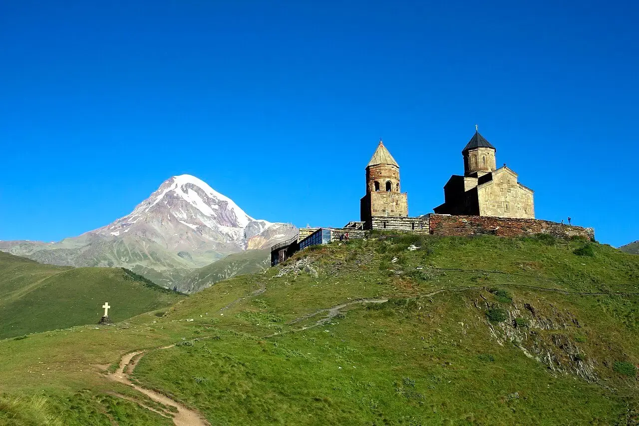 გერგეტის სამება მწვანე ქედზე, უკან თოვლიანი მყინვარწვერი